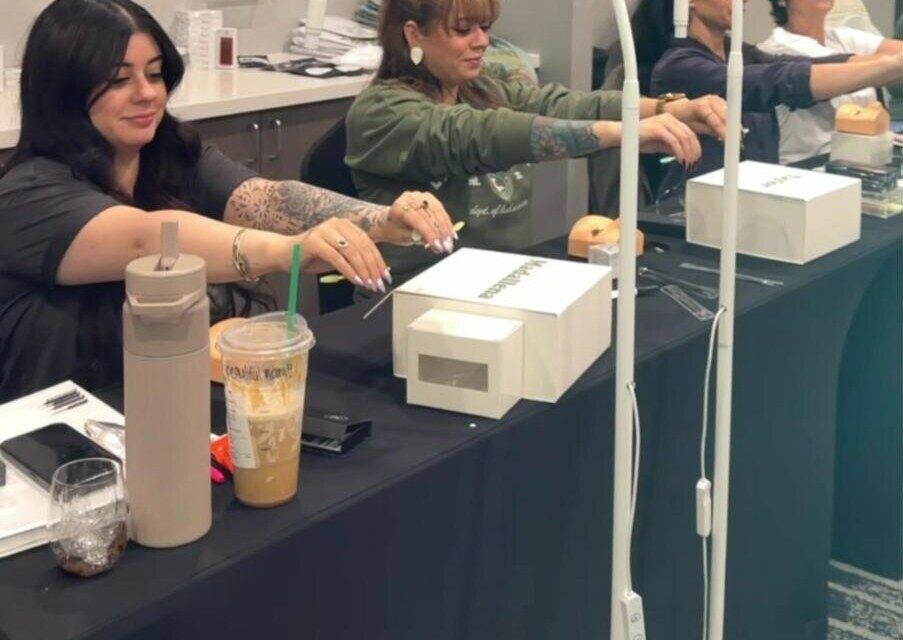 Students practicing lash application at a training table
