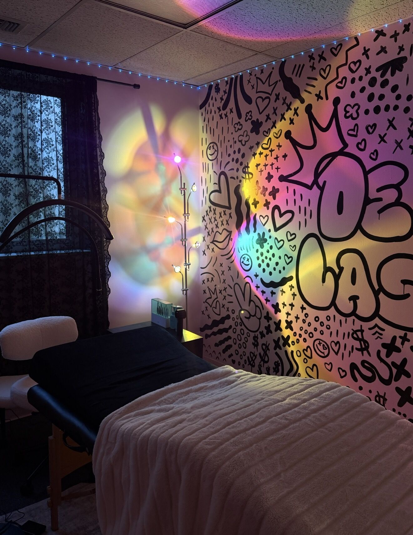 A De Voe Lashes room, lit pink and gold, with the hand painted mural