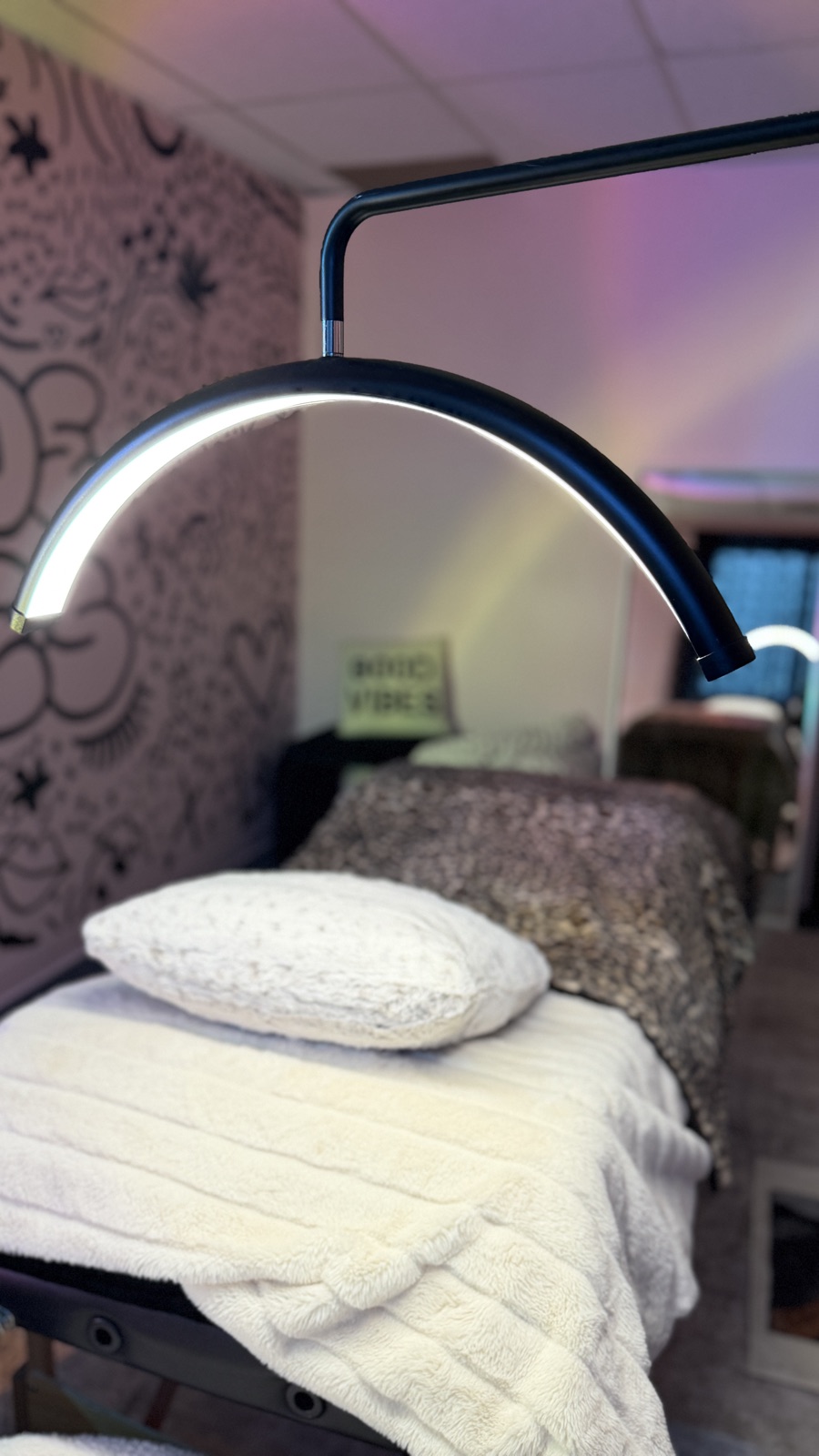 A lash bed under a ring light, with the doodle mural behind it